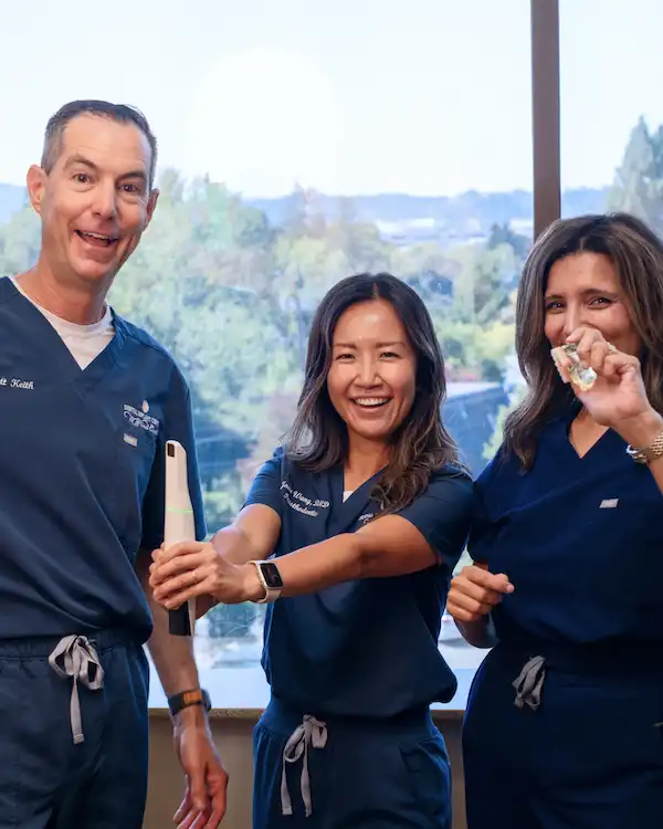 Team at Dental Implant Center at Walnut Creek holding pieces of a intraoral camera, dental implant: crown, post, and whole implant from Dental Implant Center at Walnut Creek in Walnut Creek, CA