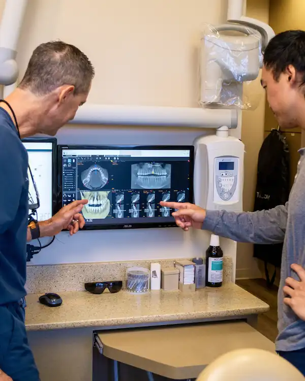 Dr. Keith and a patient pointing at Single Tooth Replacement dental implant placed in the front teeth