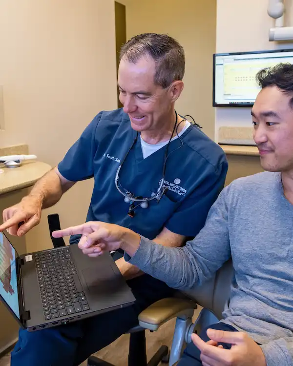 Dr. Keith with a patient pointing at the laptop screen, smiling about Sinus Lift in Walnut Creek, CA