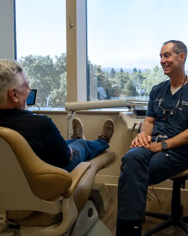 A man smiling while talking to a dentist at Dental Implant Center at Walnut Creek, Walnut Creek, CA 